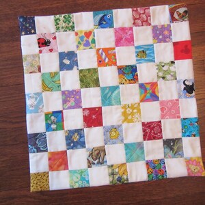 May include: A colorful patchwork quilt with a variety of patterns and designs, including animals, flowers, and geometric shapes. The quilt is made up of squares of different fabrics sewn together.