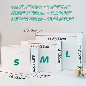 May include: Three white gift bags labeled S, M, and L. The bags have measurements in inches and centimeters. The smallest bag is 9.6" x 4" x 6.8", the medium bag is 11.2" x 4" x 8", and the largest bag is 13.2" x 4" x 11.2".