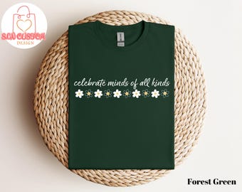 May include: Forest green t-shirt with the text "celebrate minds of all kinds" and a row of white daisies with yellow centers.