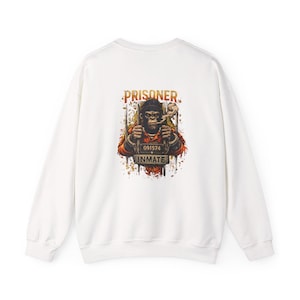 Peut inclure: Sweat-shirt blanc avec un dessin d'un gorille fumant une cigarette. Les mots "PRISONER" et "INMATE" sont au-dessus et en dessous du gorille. Le gorille porte un chapeau et a un numéro de prisonnier.