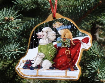 Può includere: Ornamento natalizio in legno raffigurante un barboncino con un maglione verde e un cagnolino con una sciarpa blu su una slitta. Un sacco rosso con regali è dietro di loro. L'ornamento è appeso a un nastro rosso.