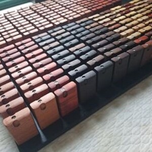 May include: A collection of small wooden boxes in various shades of brown, red, and black. The boxes are arranged in rows on a black surface.
