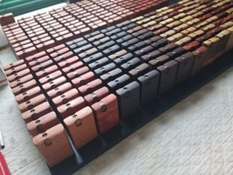 May include: A collection of small wooden boxes in various shades of brown, red, and black. The boxes are arranged in rows on a black surface.