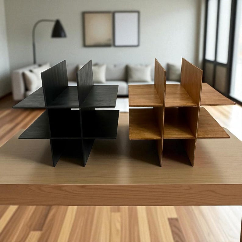 May include: Two wooden wine racks, one black and one natural wood, are displayed on a light-colored wooden table. Each rack has a unique intersecting design with multiple compartments, perfect for storing wine bottles. The racks are approximately 12 inches tall and 12 inches wide.