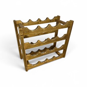 May include: A wooden wine rack with a golden-brown finish. The rack is designed to hold multiple bottles, with curved slots to cradle each bottle. The structure is made of interlocking wooden pieces, creating a sturdy and decorative storage solution.