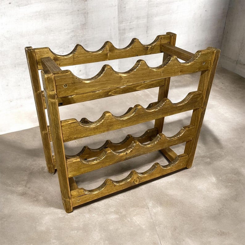May include: A wooden wine rack with a warm, golden-brown finish. The rack is designed to hold multiple bottles, with curved supports to cradle each bottle. The structure is made of sturdy wood and has a simple, functional design.