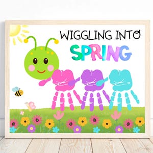 May include: A colorful handprint art project for kids. The image shows a green caterpillar with a smiling face, followed by three handprints in pink, purple, and blue. The handprints are arranged to look like the caterpillar's body. The text "Wiggling into Spring" is written at the top of the image.