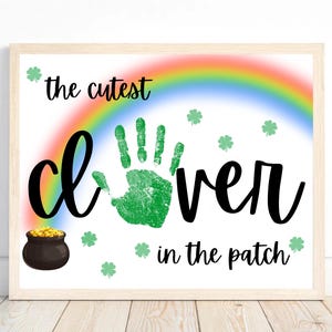 May include: A white printable sign with a rainbow, a green handprint, and the text "the cutest clover in the patch".