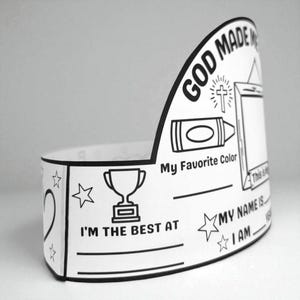 May include: A white paper crown with black outlines and text. The crown features the words "GOD MADE ME" and spaces to write "My Favourite Colour", "I'M THE BEST AT", and "MY NAME IS". Includes a crayon, cross, and trophy graphic.
