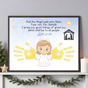May include: Framed print featuring a cartoon angel with a halo and handprints. The text reads "And the Angel said unto them...Luke 2:10." The image includes a nativity scene silhouette and star accents, perfect for Christmas decor.
