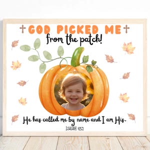 Puede incluir: Una impresión enmarcada con un niño sonriente dentro de una ilustración de calabaza naranja. El texto dice "GOD PICKED ME from the patch!" y "Me ha llamado por mi nombre y soy Suyo." con el versículo bíblico Isaías 43:1.