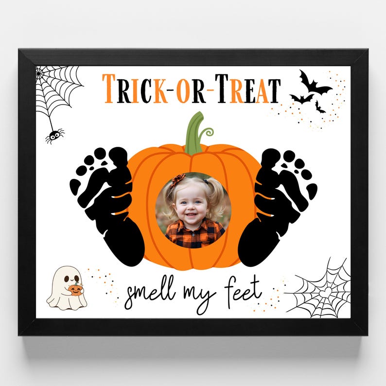 May include: Black framed Halloween-themed print with a pumpkin design. The pumpkin has a photo of a child in the center, with black footprints on either side. The words "Trick or Treat" and "smell my feet" are written on the print, along with spiderwebs, bats, and a ghost.