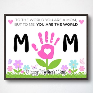 May include: A framed print with the text "TO THE WORLD YOU ARE A MOM, BUT TO ME, YOU ARE THE WORLD." The print features a pink handprint with a heart, the word "MOM", flowers, butterflies, and the text "Happy Mother's Day!"