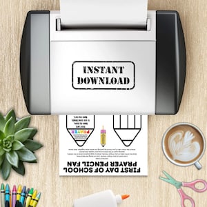 May include: A printer is shown with a printed sheet that says "Instant Download". The sheet has instructions for a "First Day of School Prayer Pencil Fan". A cup of coffee, scissors, glue, and colored pencils are also visible.
