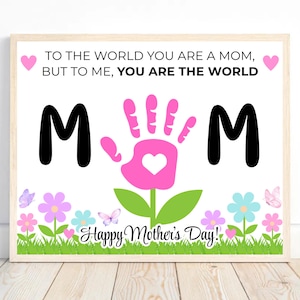May include: A framed print with the text "TO THE WORLD YOU ARE A MOM, BUT TO ME, YOU ARE THE WORLD." The word "MOM" is displayed with a pink handprint in the center. The bottom features flowers, butterflies, and the text "Happy Mother's Day!"