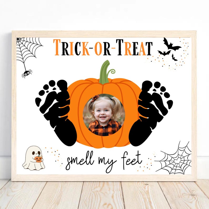 May include: Halloween-themed framed print with the words "Trick-or-Treat" in orange and black. A smiling child's photo is centered in an orange pumpkin, flanked by black footprints. Additional graphics include bats, spiders, and the phrase "smell my feet."