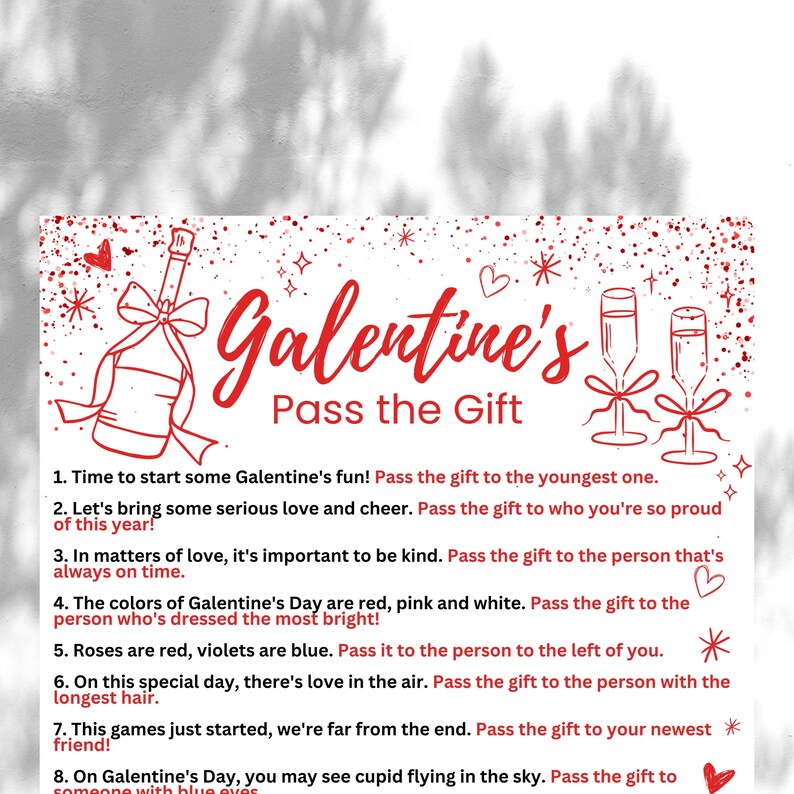 May include: A white card with red text and illustrations of a champagne bottle, two champagne flutes, and stars. The text reads "Galentine's Pass the Gift" and includes eight instructions for a Galentine's Day game.
