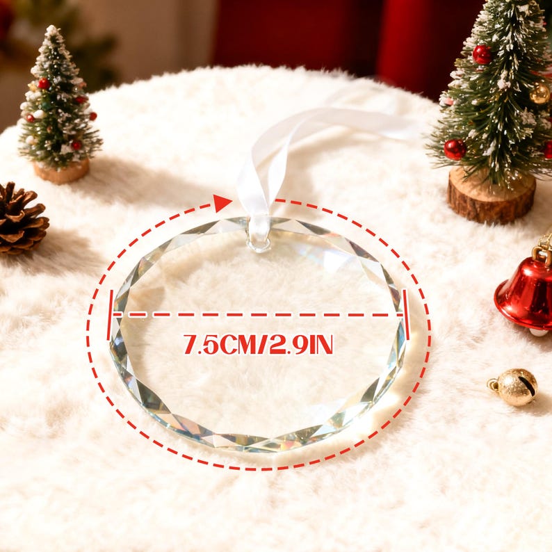 May include: A clear, circular, faceted glass ornament with a white ribbon loop for hanging. The ornament features a printed measurement graphic indicating a diameter of 7.5 cm or 2.9 inches, centered on the glass surface.