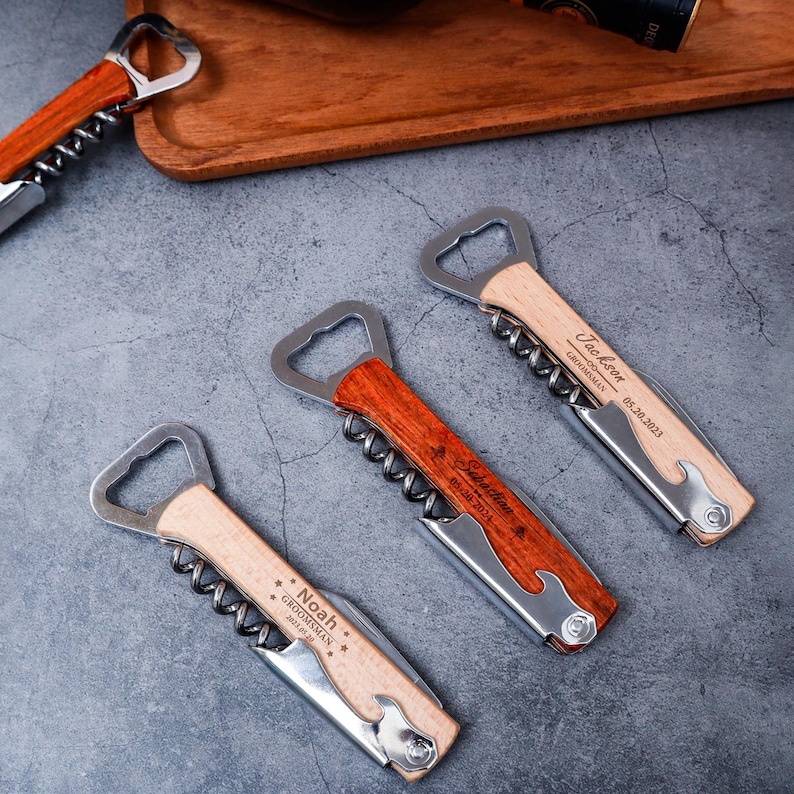 May include: A collection of personalized wooden wine bottle openers with stainless steel components. Each opener features a corkscrew, bottle opener, and a small knife. The openers are engraved with names and dates, perfect for groomsmen gifts.