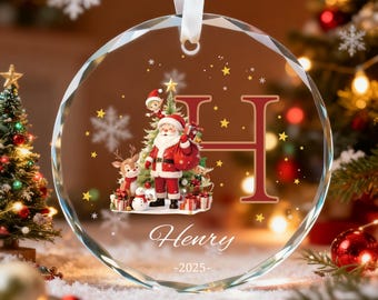 May include: A clear, round Christmas ornament with a festive Santa Claus design. The ornament features a red letter "H", the name "Henry", and the year "-2025-". It includes a white ribbon for hanging and is decorated with snowflakes and stars.