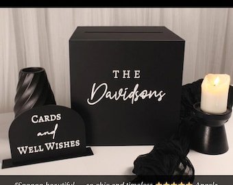 May include: A black wedding card box with the name "Davidsons" in white script. A sign that reads "Cards and Well Wishes" is in front of the box. A lit candle sits on a black pedestal. The text "Wedding Season Sale - Ends Sunday" is at the top.