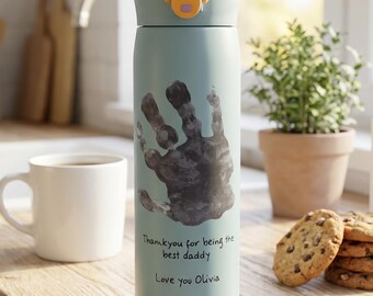 May include: A light blue stainless steel water bottle with a black handprint graphic, featuring the printed text "Thank you for being the best daddy" and "Love you Olivia" in black, topped with a black and yellow locking lid mechanism.