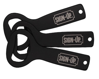 May include: Three black bottle openers with the text "SIGN-UP" in a white rectangular box. Each opener has a circular opening for leverage and a small hole at the end. The openers are arranged in a slightly overlapping fan shape.