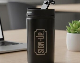 May include: A black travel mug with the text "SIGN-UP" in a rectangular frame. The mug is on a wooden desk, next to a laptop, a small succulent in a white pot, a French press, and a white mug.