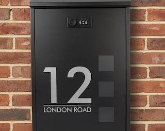 May include: A black mailbox with the number 12 and the words "LONDON ROAD" in silver lettering. The mailbox is mounted on a red brick wall. The mailbox has a combination lock.