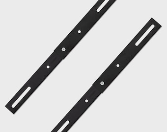 May include: Two black metal mounting brackets with slotted holes and screw holes. The brackets are angled and appear to be for mounting a shelf or other hardware. The brackets are made of a matte black metal.