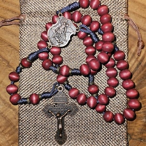 Rosario del vino nuovo con grani rossi, crocifisso in rame del Perdono e medaglia centrale di San Michele, rosario in paracord