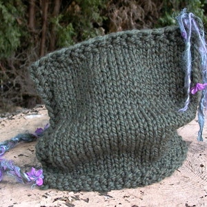 May include: A dark green knitted cowl with a long, frayed purple and blue cord attached. The cord has small purple flowers attached to it.