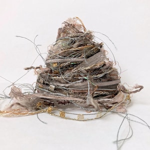 May include: A pile of tangled yarn in shades of brown, beige, and gold. The yarn is made of different textures, including fluffy, silky, and metallic threads.