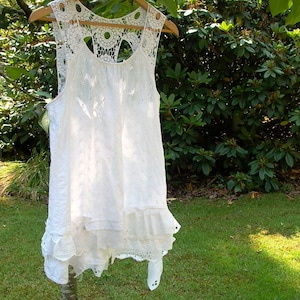 May include: White crochet lace sleeveless top with a scalloped hem and a delicate floral pattern.