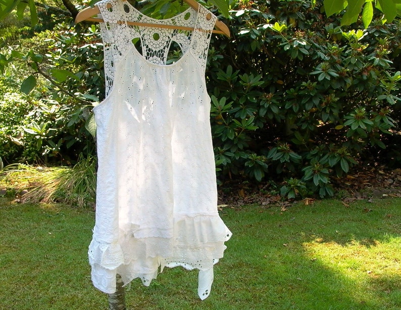 May include: White crochet lace sleeveless top with a scalloped hem and a delicate floral pattern.