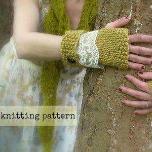 May include: A pair of knitted fingerless gloves in a mustard yellow color with a white lace trim. The gloves are worn by a person holding a tree trunk.