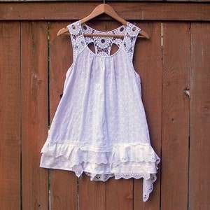 May include: White eyelet dress with a crocheted lace bodice and a tiered ruffle skirt.