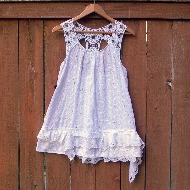 May include: White eyelet dress with a crocheted lace bodice and a tiered ruffle skirt.