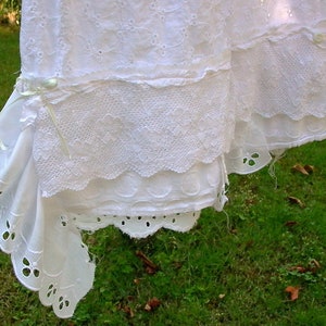 May include: White cotton lace trim with scalloped edges and a delicate floral pattern. The lace is hanging on a clothesline.