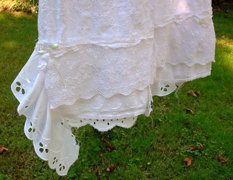 May include: White cotton lace trim with scalloped edges and a delicate floral pattern. The lace is hanging on a clothesline.