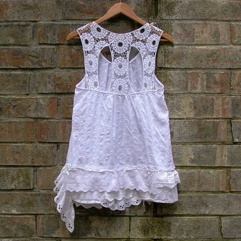 May include: White crochet top with a scalloped hem and a lace back. The top has a loose fit and is perfect for summer.