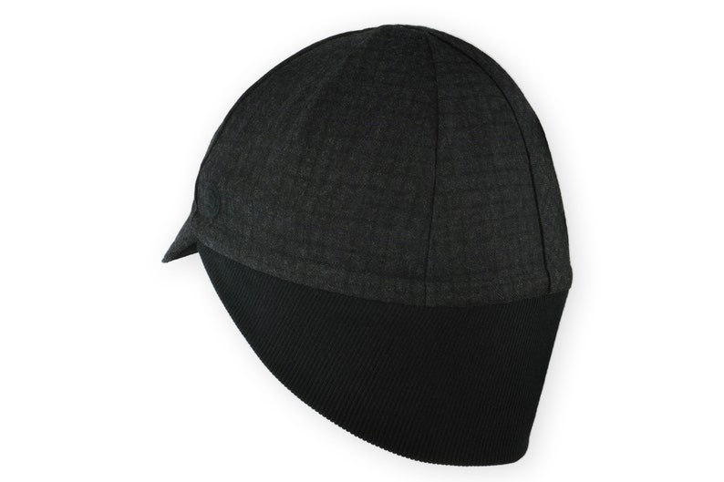 Equinox Winter Cap handmade with short brim by Red Dots Cycling. 100% wool plaid fabric, charcoal grey/black plaid and purple accent.
The black ear flap is double-layered, made from Bamboo cotton ribbed. Red Dots black logo embroidered on side panel.