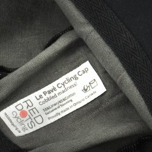 Le Pave Cycling Cap,
Close-up of our sewn-in label. Including; cap name, fabric content, washing care and sizing.