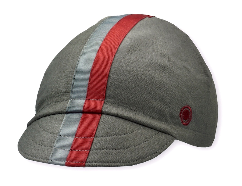 Le Pave Cycling Cap,
A four-panel, Gray linen/cotton hat with a short brim. Gray and burgundy ribbon runs from the back of the cap to the bottom of the brim. Red Dots embroidered burgundy logo on the side panel.