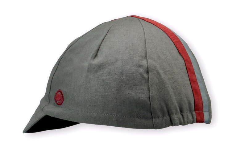 Le Pave Cycling Cap,
A four-panel, Gray linen/cotton hat with black under brim. Gray and burgundy ribbon runs from the back of the cap to the bottom of the brim. Red Dots embroidered burgundy logo on the side panel.
