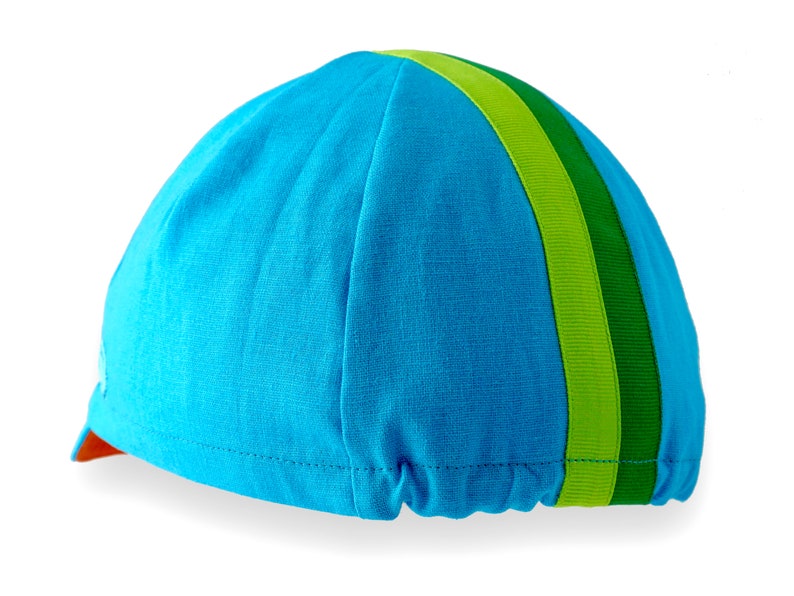 Ardennes Cycling Cap.
A four-panel, Teal linen/cotton hat with orange under brim. Green, lime ribbon from the back of the cap to the bottom of the brim. Red Dots embroidered teal logo on the side panel.