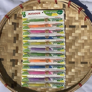 May include: A pack of 12 assorted gel pens, labelled "Pin-Point" and "Matador". The pens are in a variety of colours, including blue, green, pink, yellow, and purple. The pens are packaged in clear plastic and have a green and yellow label.