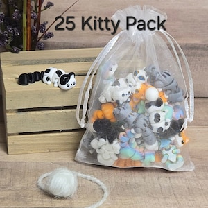 K&ouml;nnte beinhalten: Ein wei&szlig;er Organzabag gef&uuml;llt mit 25 kleinen, bunten Katzenfiguren. Die Tasche ist mit einem wei&szlig;en Band gebunden und tr&auml;gt den Aufdruck "25 Kitty Pack".