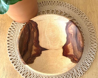 May include: A round wooden bowl featuring a light-colored center and dark, contrasting wood grain patterns on the sides. The bowl has a smooth, polished finish and a circular shape, showcasing the natural variations and textures of the wood grain.