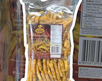 以下が含まれることがあります： シンガリングブランドの焼き菓子が入った透明なビニール袋。袋にはブランド名「サー・ノーマン・ベイカー」と商品名「シンガリング」のラベルが貼られている。焼き菓子は金色がかった茶色で、細くてカリカリの棒状になっている。